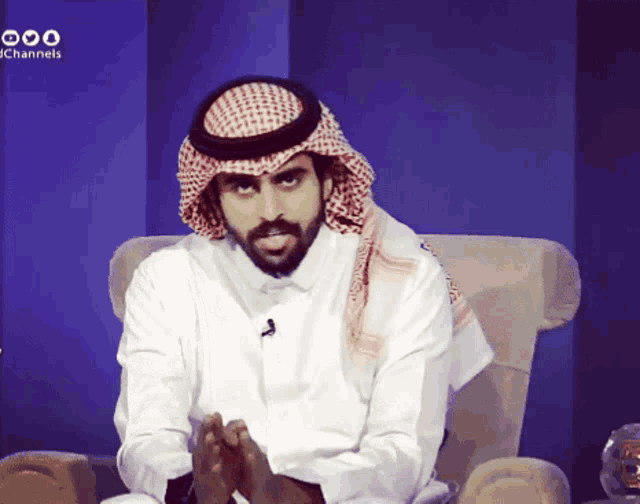 a man with a beard and a head scarf is sitting in a chair with a blue background that says jc channels