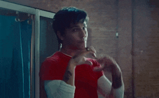 a man in a red shirt making a heart with his hands
