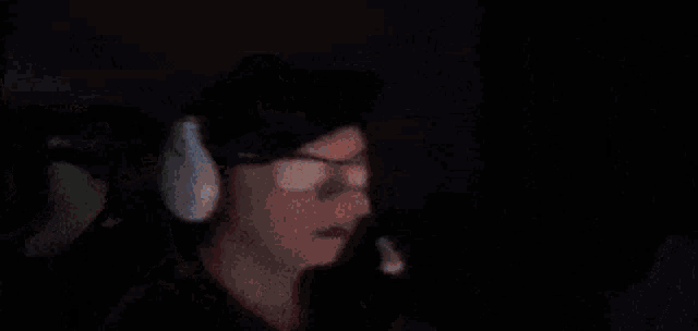 a person wearing headphones and a hat is sitting in front of a computer screen .