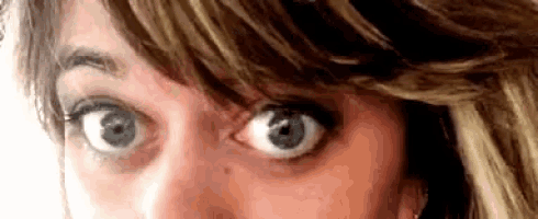a close up of a woman 's face with a very wide eye