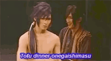 two shirtless men are standing next to each other on a stage and one of them is talking about tofu dinner .