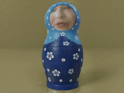 a blue green and orange russian nesting doll with a woman 's face on it