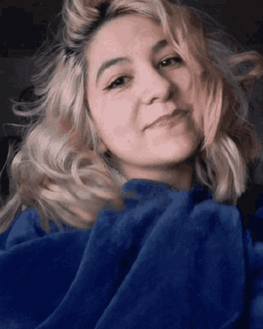 a woman with blonde hair wearing a blue sweater