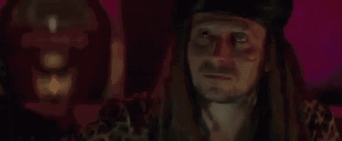 a man with long hair and a beard is wearing a hat and a leopard print shirt .