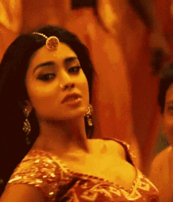 a close up of a woman wearing a red and gold dress and a headpiece .