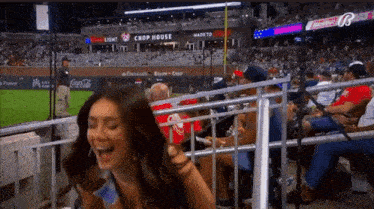 a woman is laughing in the stands at a baseball game sponsored by coca cola