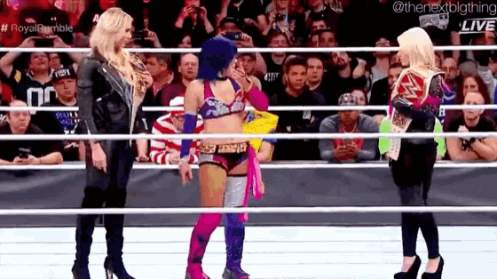 a group of women standing in a wrestling ring .