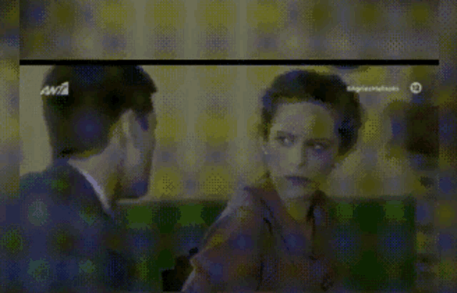 a man in a suit and tie talks to a woman in a blurry image