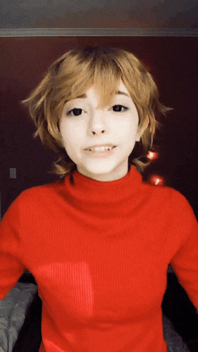 a woman wearing a red turtleneck sweater and a blonde wig