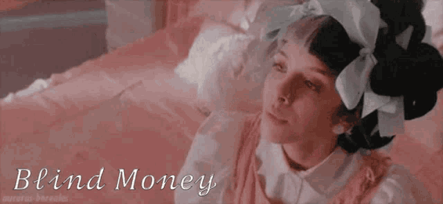 a girl with a bow in her hair is laying on a bed with blind money written on the bottom