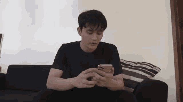 a man is sitting on a couch using a cell phone .