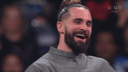 a man with a beard is smiling in front of a tv screen that says ' usa ' on it