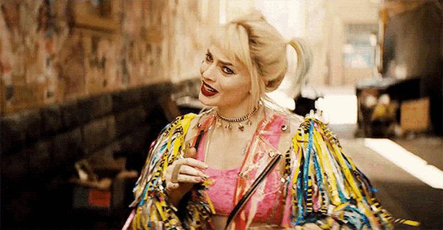 a woman in a colorful jacket is walking down a hallway holding a drink .