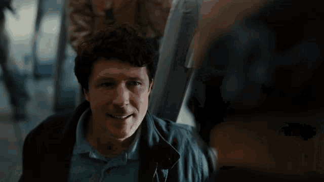 a man in a blue jacket is looking at another man in a blue shirt
