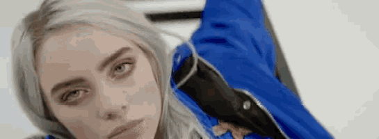 a close up of a woman wearing a blue jacket and looking at the camera .