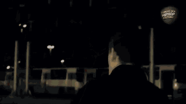 a man in a black jacket is standing in a dark room .