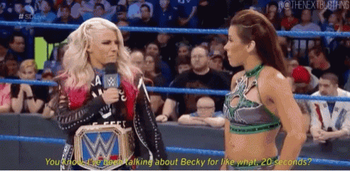 two women are talking in a wrestling ring and one of them is wearing a wwe belt