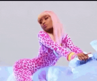 a woman in a pink giraffe print onesie is kneeling down on a bed holding a bottle of water .