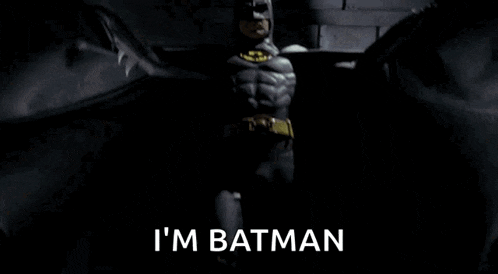 a man in a batman costume says i 'm batman in a dark room