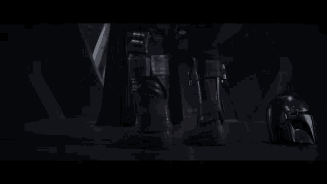 a person standing next to a baby yoda and a helmet in the dark