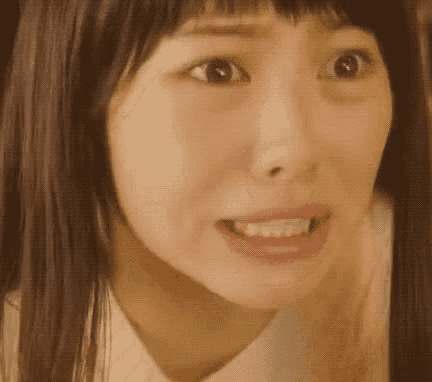 a close up of a woman 's face with a surprised expression on her face .