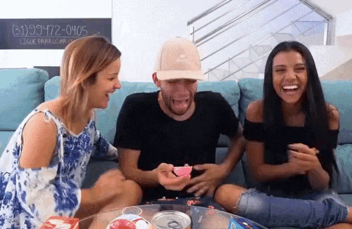a group of people are sitting on a couch laughing and one of them has a phone number on the wall