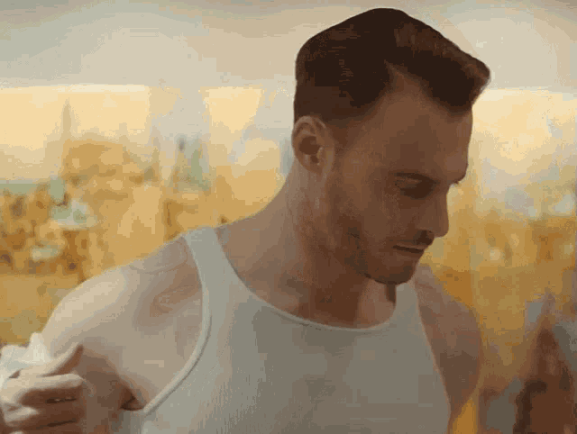 a man is wearing a white tank top and giving a thumbs up