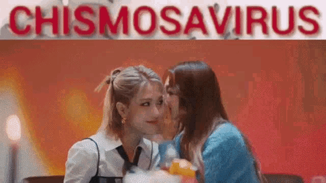 two women are kissing in front of a sign that says chismosaurus