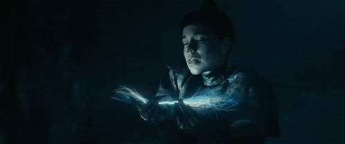 a person in a dark room with a light coming out of their hands