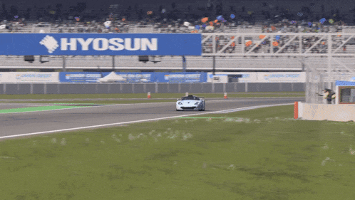 a car is driving on a race track with a sign for hyosun in the background