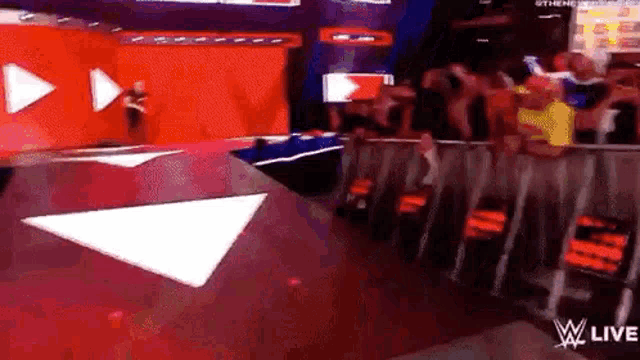 a man is standing on a stage in front of a crowd at a wrestling match .