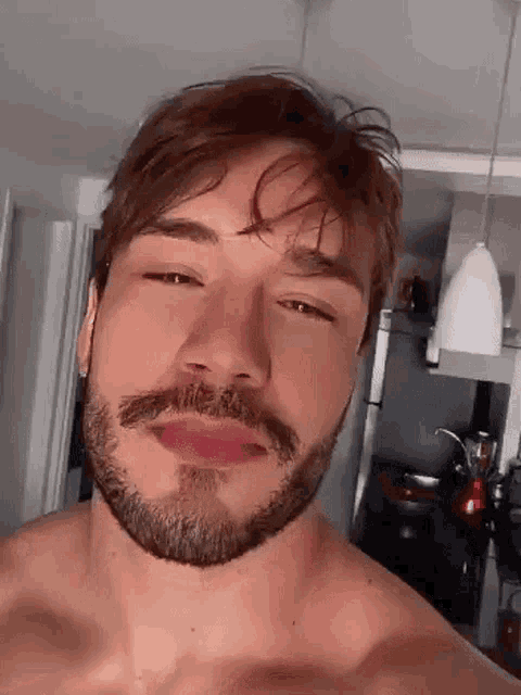 a shirtless man with a beard is taking a selfie .