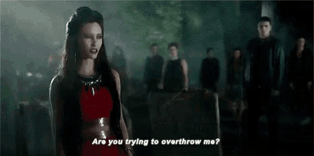 a woman in a red dress is talking to a group of people in a cemetery .