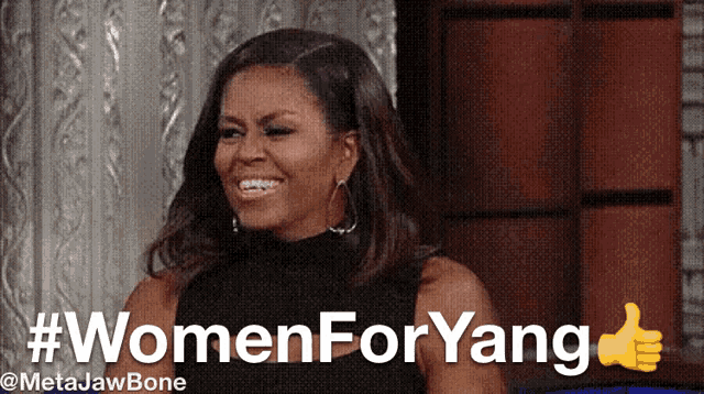 a woman giving a thumbs up in front of a sign that says #womenforyang
