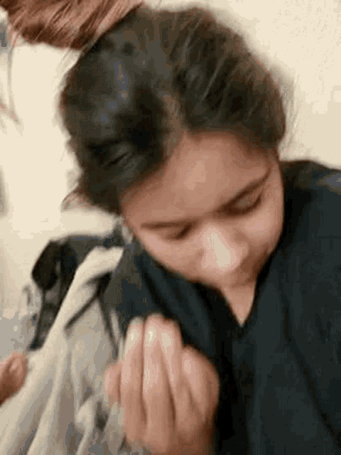 a woman is sitting on a bed with her hair in a bun and making a face .