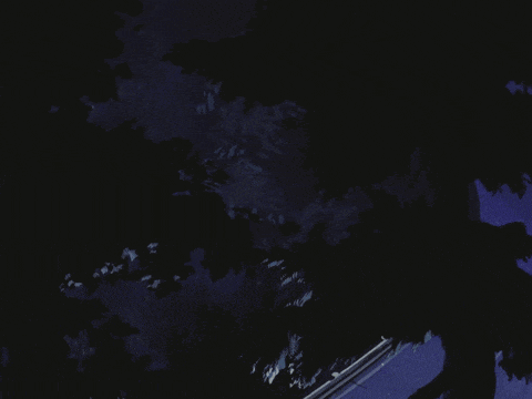 a car is driving down a road at night with the headlights on
