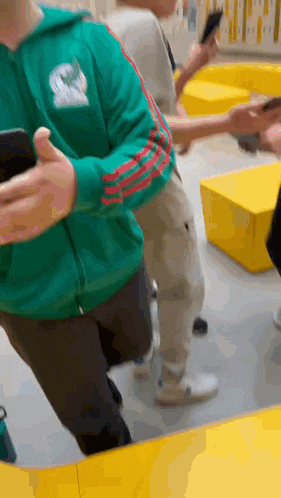 a man in a green adidas sweatshirt is holding a cell phone