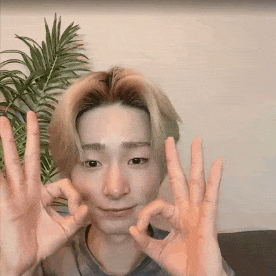 a young man is making an ok sign with his hands while sitting on a couch .
