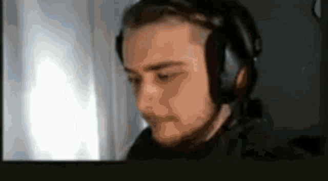 a man with a beard is wearing headphones and looking at a computer screen .