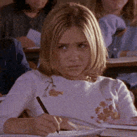 a girl is writing in a notebook while sitting at a desk