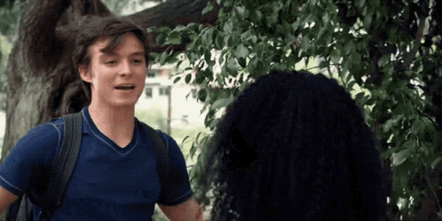 a man in a blue shirt talking to a woman with curly hair