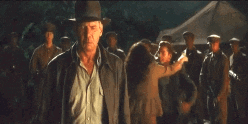 a man in a hat stands in front of a group of people and says mom in yellow letters