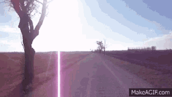 the sun is shining through the trees on the side of the road