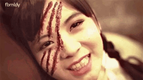 a close up of a woman with blood on her face and claw marks on her face .