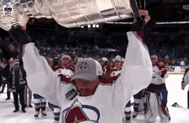 a hockey player holds up a trophy that says sn on the bottom