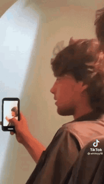 a man is taking a picture of himself in a mirror with a cell phone .