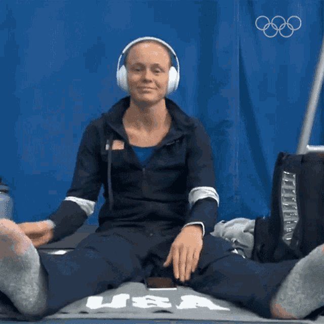 a woman wearing headphones is sitting on a mat with the word usa on it