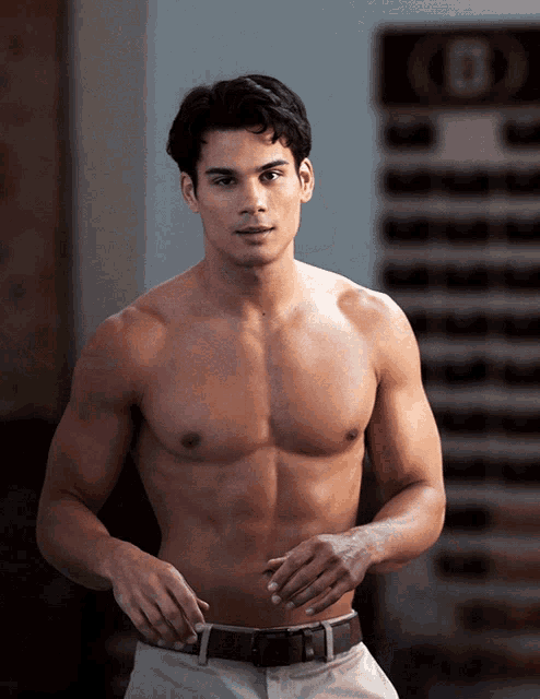 a shirtless man is standing in front of a sign that says b on it