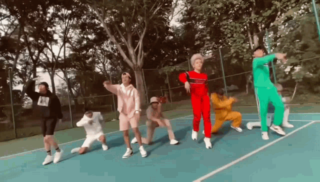 a group of people are dancing together on a tennis court