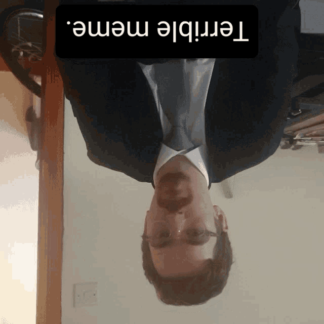 a man in a suit and tie is upside down with a terrible meme written on the bottom
